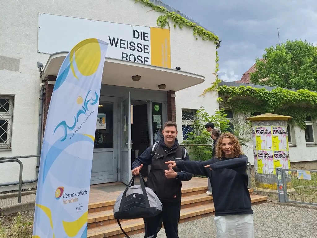 Eine Schülerin und ein Schüler zeigen auf den Eingang der Junify-Veranstaltung